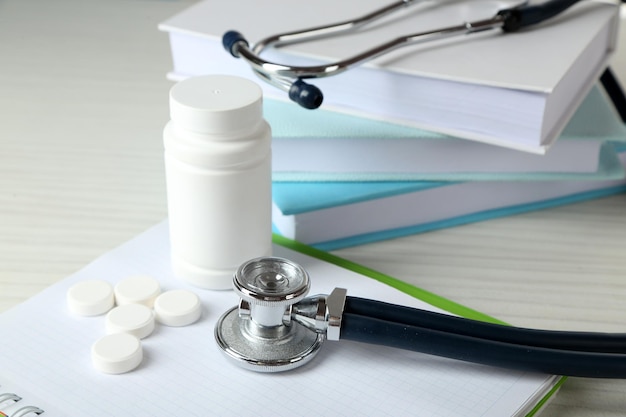 Estetoscópio médico com livros e tablet na mesa de madeira