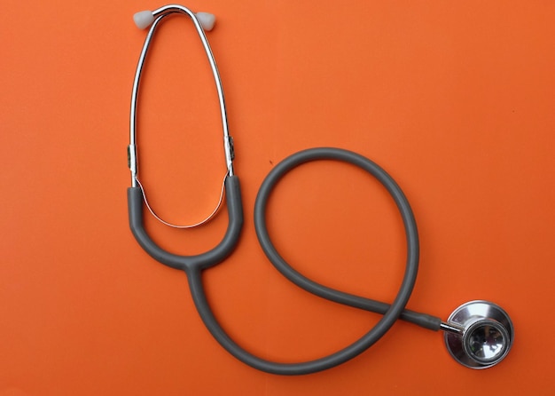 Estetoscópio médico plano em fundo laranja na secretária do médico