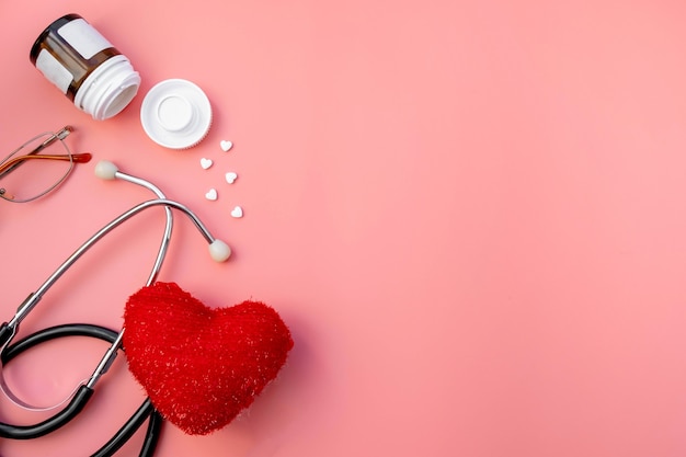 Estetoscopio negro con corazón rojo y tabletas de medicina de médico para chequeo en rosa