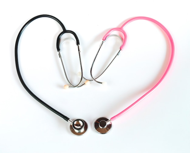 Estetoscopio negro y estetoscopio rosa haciendo una forma de corazón sobre fondo blanco.