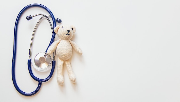 Foto estetoscopio y oso de peluche aislar sobre un fondo blanco. enfoque selectivo.