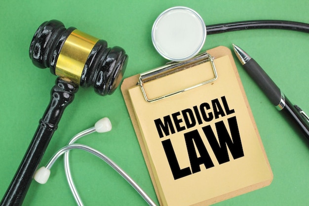 Estetoscopio pluma martillo del juez y tablero de libro marrón con palabras de derecho médico conceptos médicos médico