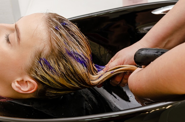 Estilista aplicar colorante champú púrpura después de teñir el cabello.