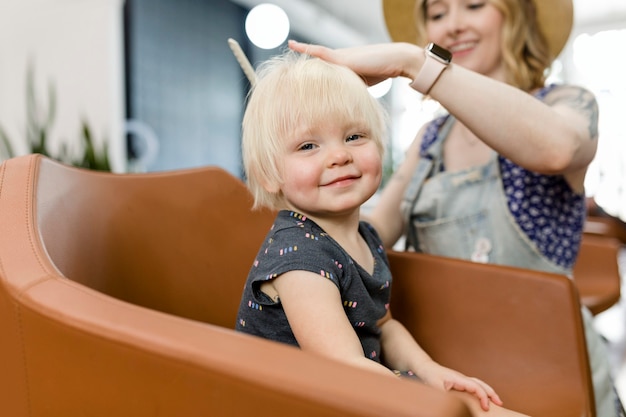 Estilista dándole un corte de pelo a un adorable niño rubio