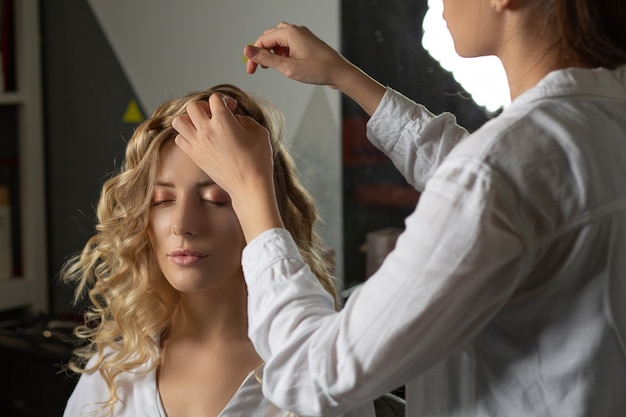 Estilista de cabelo profissional tocando o cabelo da cliente após estilizá-la em um salão de beleza. Foto de close