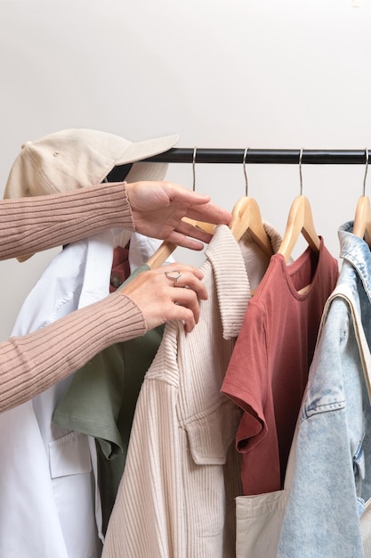 Foto estilista de moda escolhe roupas no corrimão no showroom roupas femininas básicas e bolsa ecológica