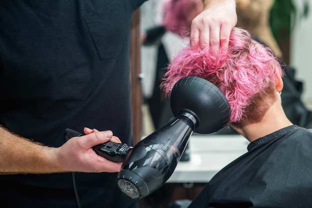 Estilista está secando o cabelo da mulher.