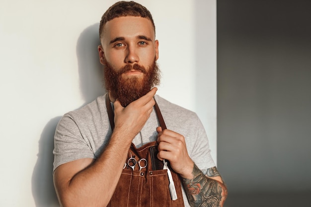 Estilista masculino acariciando la barba y mirando a la cámara