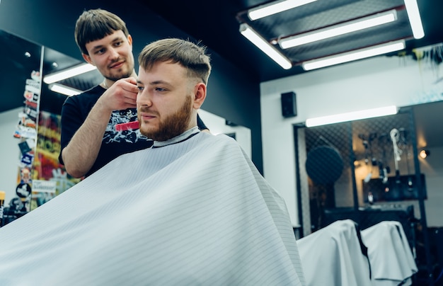 Estilista masculino cortando el cabello de un cliente