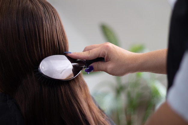 Estilista peinando el cabello de una mujer con un cepillo plateado