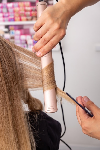 Estilista de pelo prepara mujer hace rizos peinado con rizador