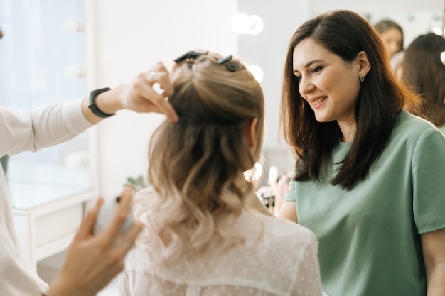 Estilista profissional e maquiador fazendo maquiagem e penteado para mulher jovem