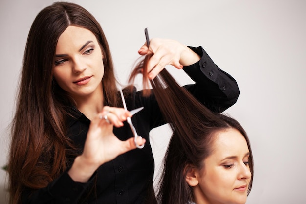 Estilista profissional faz um penteado bonito para uma jovem.