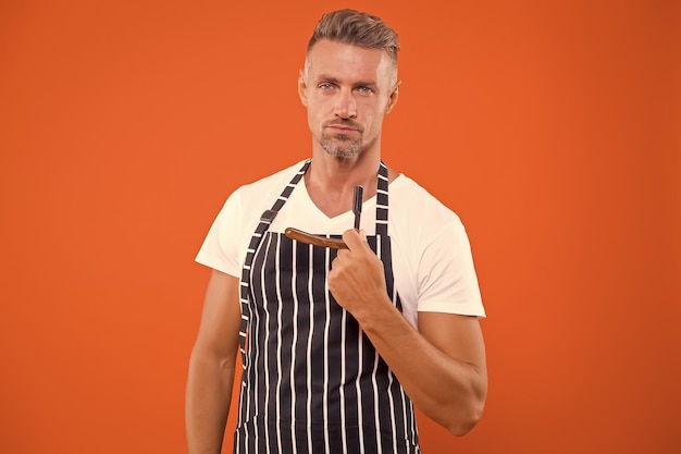 Foto el estilo de la barbería comienza aquí el barbero sostiene la navaja con fondo naranja el hombre barbudo se afeita en la barberías