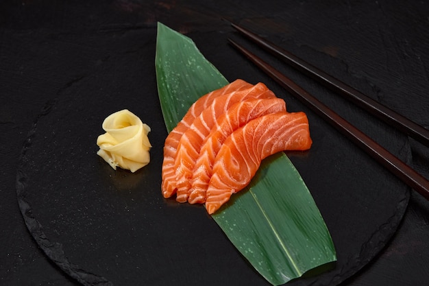 Estilo de comida japonesa Vista superior de una rodaja de salmón en hojas de bambú El sashimi de salmón es tradicional japonés Enfoque selectivo Rodajas de pescado vista superior