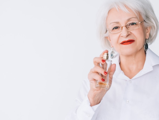 Estilo de moda mulher sênior. tendências de perfume. frasco de fragrância cara em mãos femininas.