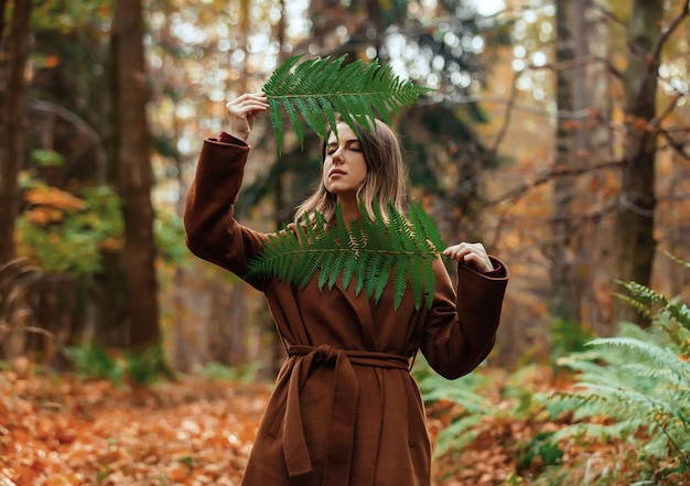 Foto estilo de mulher com ramo de samambaia em uma floresta de outono