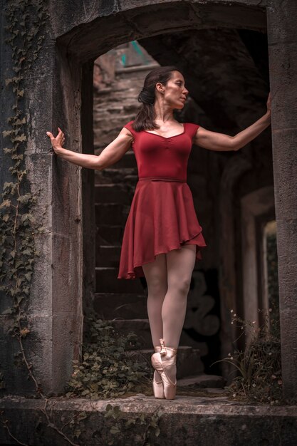 Estilo de vida, dançarina de balé menina morena com um vestido vermelho dançando balé na ponta dos pés em uma janela