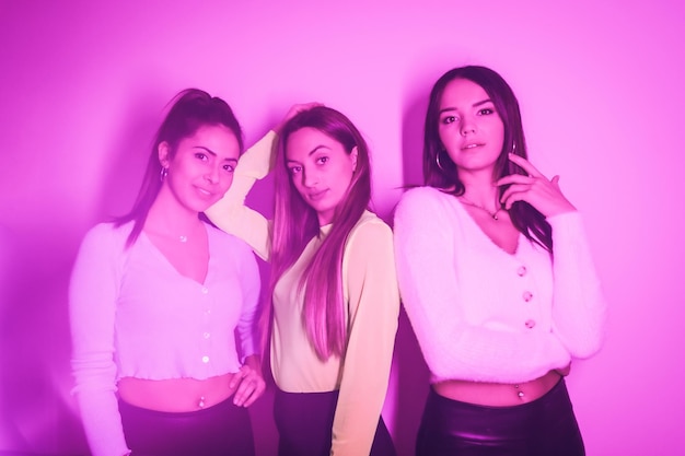 Estilo de vida de amigos festejando em uma boate com luzes de neon rosa retrato das jovens belas mulheres caucasianas