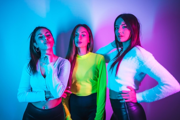 Estilo de vida de amigos festejando em uma discoteca com luzes neon azuis e rosa retrato de jovens mulheres caucasianas