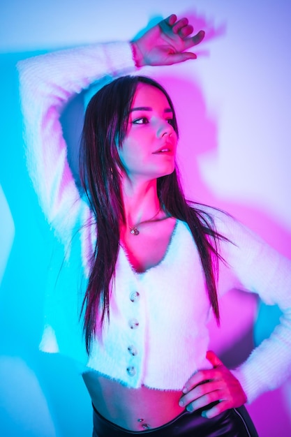 Estilo de vida de festa em uma boate com luzes de neon azul rosa retrato de uma jovem morena caucasiana em um suéter de lã