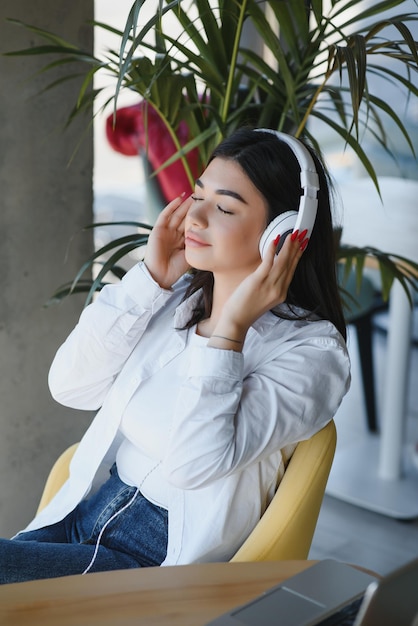 Estilo de vida de mulheres de negócios freelance sentado sozinho ele usando fones de ouvido ouvindo música nova música durante o trabalho no computador portátil na cafeteria Aluna pausa para o café enquanto fazia a lição de casa