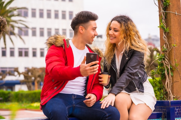 Estilo de vida de um casal caucasiano fazendo turismo de férias, em um parque da cidade, olhando coisas na internet com o celular