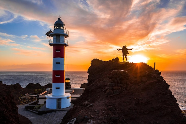 Estilo de vida de uma garota visitando o farol ao pôr do sol em Punta de Teno Tenerife