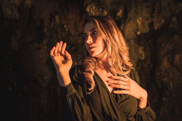 Estilo de vida de uma jovem loira caucasiana em um vestido preto dentro de uma caverna iluminada com luz amarela