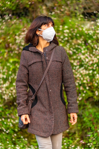 Estilo de vida de uma jovem morena com máscara caucasiana em um parque Primeiras caminhadas da pandemia de Covid19 descontrolada