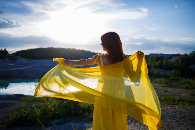 Estilo de vida de verão de uma deslumbrante mulher feliz correndo na natureza. Em um longo vestido amarelo. Humor romântico. Aproveitando o sol. Dia ensolarado. Foco seletivo