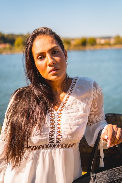 Foto estilo de vida de verão uma jovem morena latina desfrutando de um parque em um vestido branco