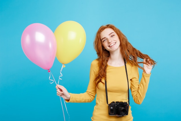 Estilo de vida e conceito de festa close-up retrato jovem linda garota atraente ruiva ruiva com balão colorido e câmera vintage azul pastel espaço de cópia de parede