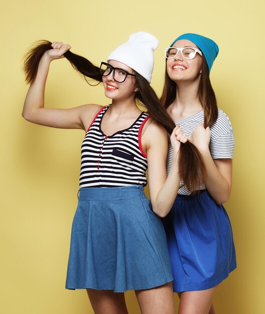 Estilo de vida e conceito de pessoas Duas jovens amigas juntas e se divertindo Olhando para a câmera Fundo amarelo