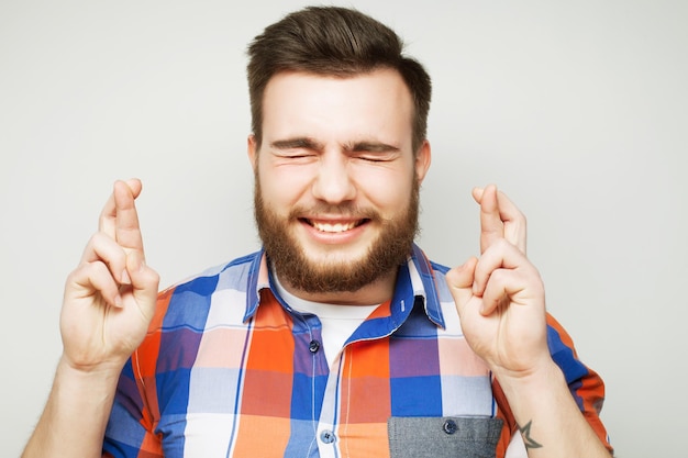 estilo de vida e conceito de pessoas À espera de um momento especial Retrato de um jovem barbudo de camisa mantendo os dedos enquanto está de pé contra um fundo branco Estilo hipster e emoções positivas