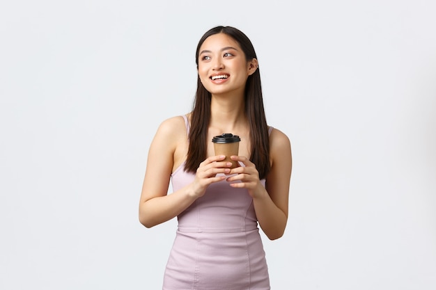 Estilo de vida, emoções das pessoas e conceito de glamour. Menina asiática sonhadora de vestido, sorrindo e olhando para a imagem do canto superior esquerdo