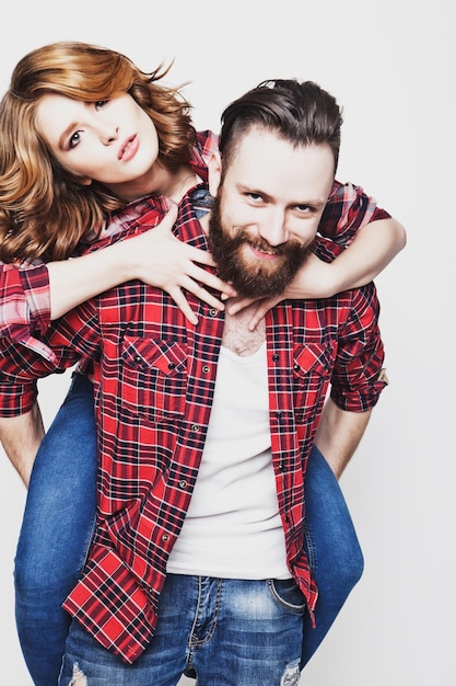 Estilo de vida, felicidade e conceito de pessoas: Feliz casal apaixonado. Jovem pegando carona com sua namorada. Estúdio atirou sobre fundo branco. Fotos de tonificação na moda especiais.