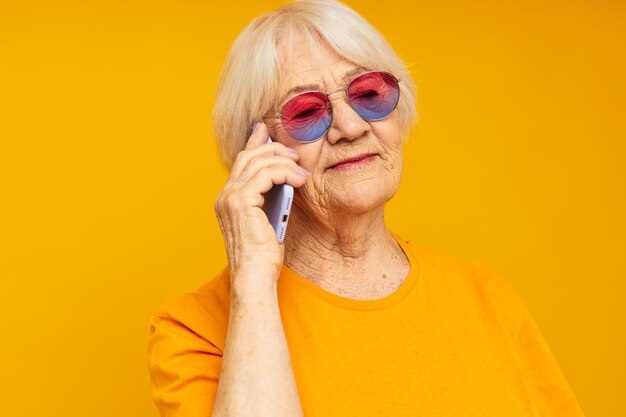 Estilo de vida feliz de mulher idosa sorridente em camisetas amarelas com emoções de telefone fechado