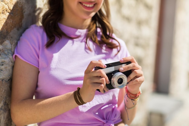 Foto estilo de vida, fotografia e conceito de pessoas - close de adolescente sorridente ou mulher jovem com câmera vintage ao ar livre