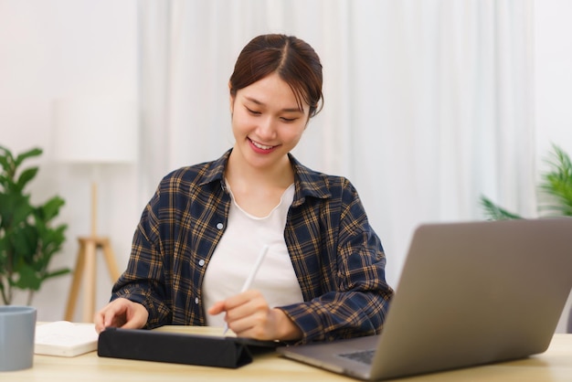 Estilo de vida no conceito de sala de estar Jovem asiática escrevendo em tablet para trabalhar online em casa