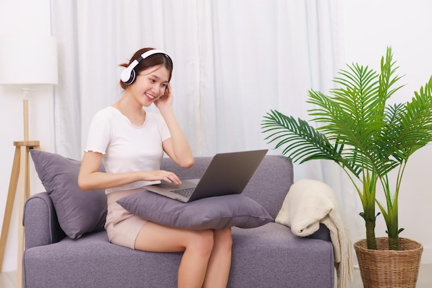 Estilo de vida no conceito de sala de estar Jovem asiática no fone de ouvido para assistir filme no laptop