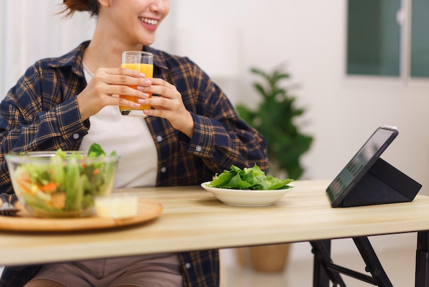 Estilo de vida no conceito de sala de estar Mulher asiática assistindo filme em tablet e bebendo suco de laranja