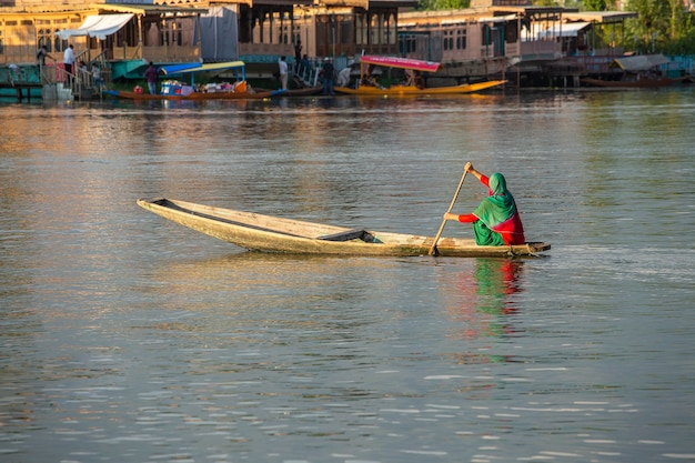 Estilo de vida no lago Dal, a população local usa o Shikara, um pequeno barco para transporte no lago de Srinagar, Jammu e no estado de Caxemira, na Índia. Mulher indiana em um barco