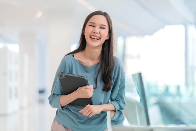 Estilo de vida nômade digital mulher asiática mão usando tablet trabalhando branco fique do lado de fora com luz natural jovem mulher asiática sorrindo alegre liberdade sorriso positivo mão em pé segure o tablet