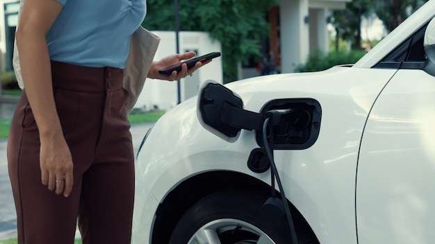 Estilo de vida progressivo de uma mulher moderna que acaba de voltar do trabalho em um veículo elétrico que está sendo carregado em casa Veículo elétrico movido por energia limpa sustentável