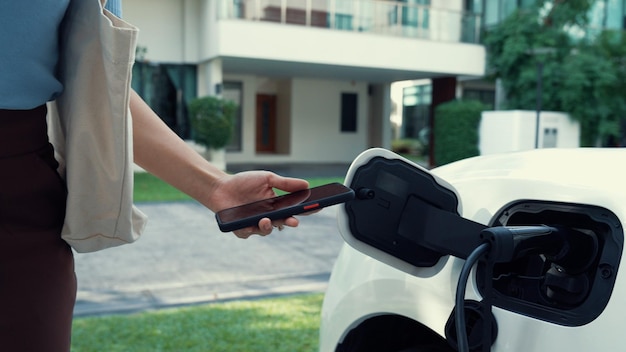 Estilo de vida progressivo de uma mulher moderna que acabou de voltar do trabalho em um veículo elétrico que está sendo carregado em casa Veículo elétrico movido a energia limpa e sustentável