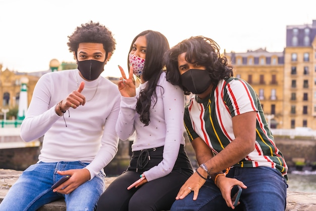 Estilo de vida, retrato de três amigos se divertindo na rua com máscaras faciais.