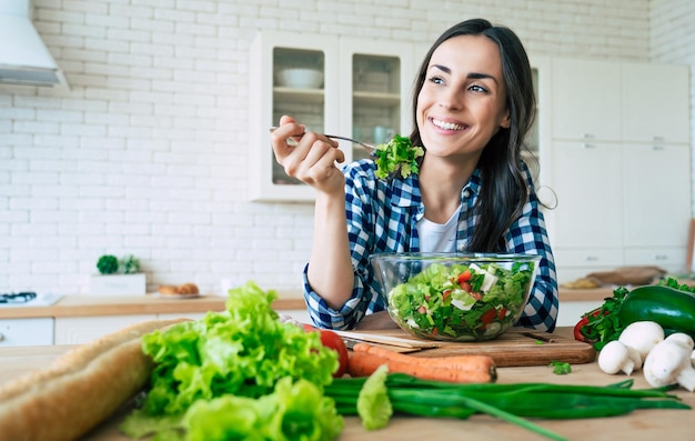 Estilo de vida saudável. boa vida. comida orgânica. legumes. feche o retrato de uma linda jovem bonita e feliz enquanto ela experimenta uma saborosa salada vegana na cozinha de casa