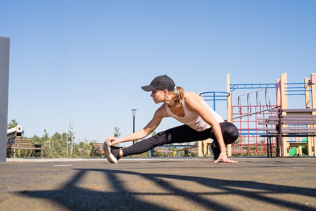 Estilo de vida saudável e ativo. Esportes e condicionamento físico. Mulher feliz em roupas esportivas, malhando na quadra de esportes em um dia ensolarado de verão, aquecendo