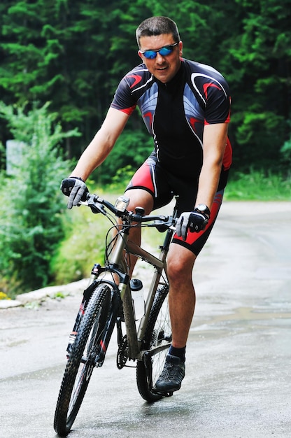 estilo de vida saudável e conceito de fitness com homem de bicicleta de montagem ao ar livre